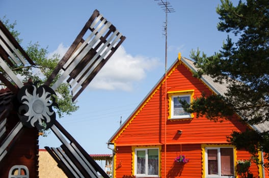 country red wooden house and brown decorative mill wind in summer