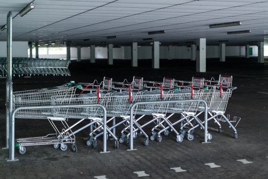 Rows of shopping carts in abandoned car park near entrance of closed supermarket due to public holiday