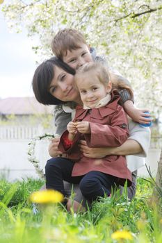 Happy mother and two children hugging among blooming garden