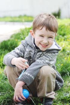 Happy boy with Easter egg outdoor in spring