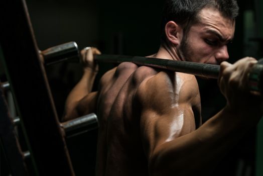 Young Man Performing Barbell Squats - One Of The Best Body Building Exercise For Legs