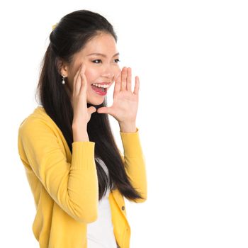 Young Asian girl shouting loud, hands next to the mouth, isolated on white background