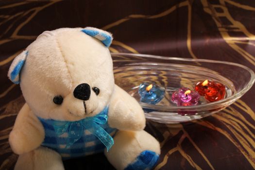 cute teddy bear sitting near floating candle