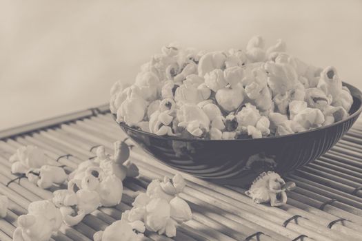 popcorn over filled in bowl and some corn on floor, vintage edited