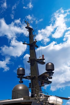 Detail of luxury black yacht with navigation equipment, radar and antennas on blue sky with clouds