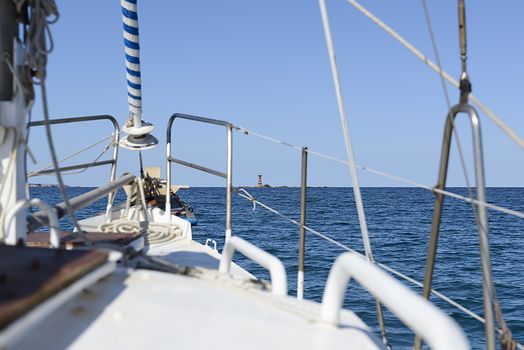 Bow of the boat pointing towards the lighthouse. Island of Sardinia.