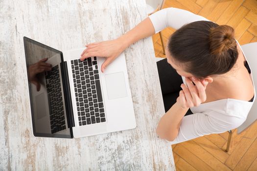 A young adult woman working on a laptop.