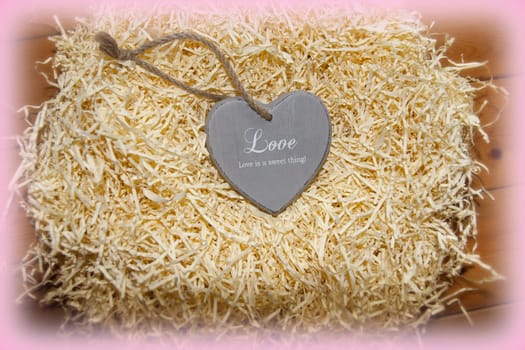 single wooden love heart in a love nest made of straw on floor boards