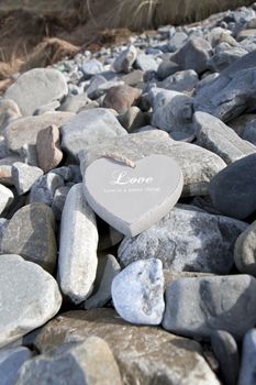 single inscribed grey wooden love heart on a pebble beach in Ireland