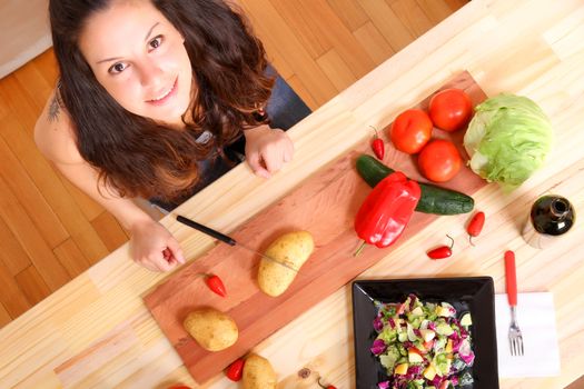 A young woman cutting vegetables ion the kitchen.