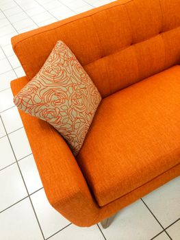Modern orange sofa with decorative cushion.