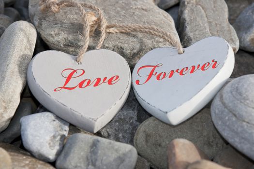 two wooden love hearts on the rocks of a beach