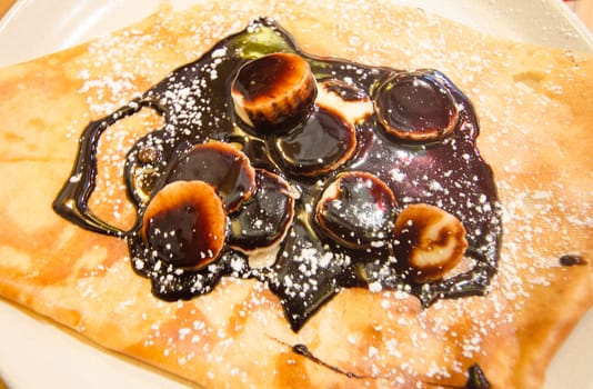 A banana crepe topped with a chocolate.