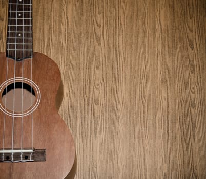 The ukulele is placed on a vintage wooden floor.