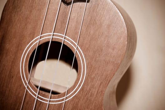 The ukulele is placed on a vintage wooden floor.