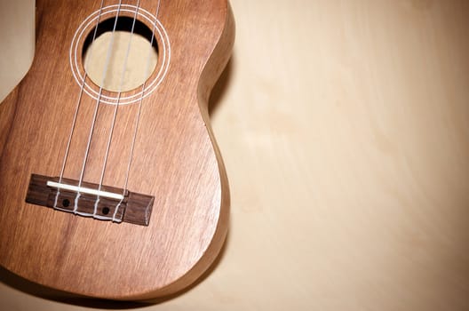 The ukulele is placed on a vintage wooden floor.