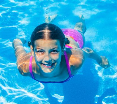 The cute girl swimming underwater and smiling