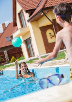 Cute happy girl playing with boy in swimming pool