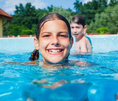 Cute happy girl playing in swimming pool