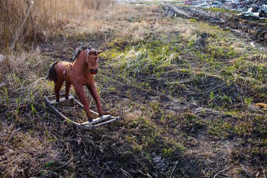 Old threadbare rocking horse thrown away to the dump in the field