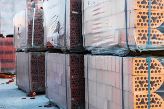 Stacks of silicate bricks on wooden pallets and in polyethylene 