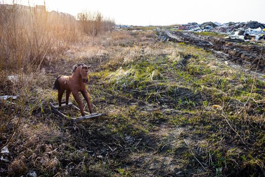 Old threadbare rocking horse thrown away to the dump in the field