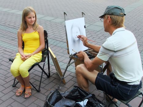 Street artist painting portrait of young girl, Moscow, Russia