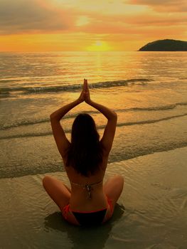 Young woman in bikini sitting on a beach at sunset, Langkawi island, Malaysia, Southeast Asia