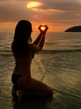 Young woman shaping heart with her hands at sunset, Langkawi island, Malaysia, Southeast Asia