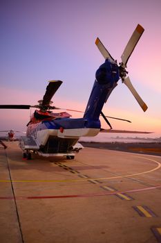 offshore oil rig helicopter on the apron next to runway with sunrise background