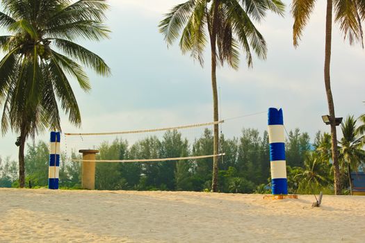 Beach volleyball net with white sand and coconut tree