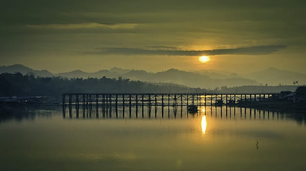 The sun's rising in the morning behind the destoyed wooden bridge.