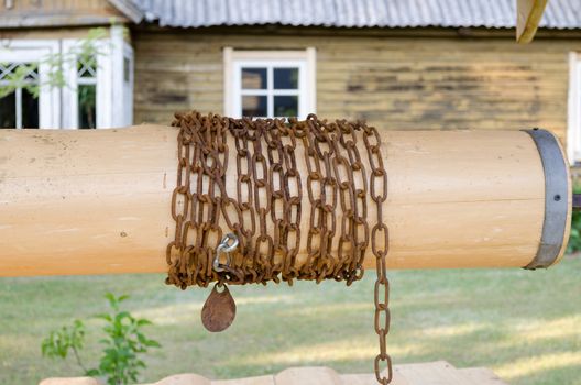 close up of wooden well roller with chain in country yard