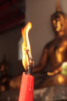 A single burning red candle at Wat Pho in bangkok, thailand.