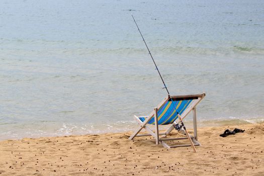 Fishing rod is placed beside the chair beach.