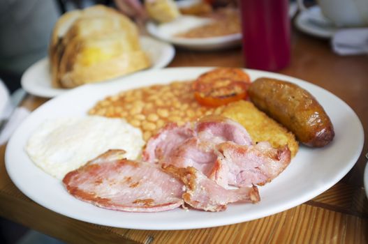 Traditional English breakfast, egg, bacon, sausage and beans served in a restaurant in London. Very short depth-of-field.
