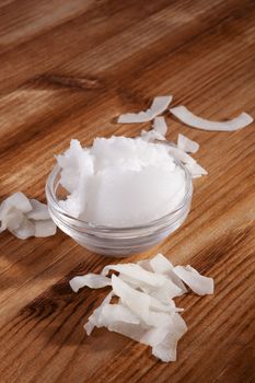 Coconut oil and dry coconut flakes on brown wooden background. Healthy cooking.