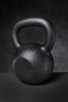 A rough and tough heavy cast iron kettlebell on grey background