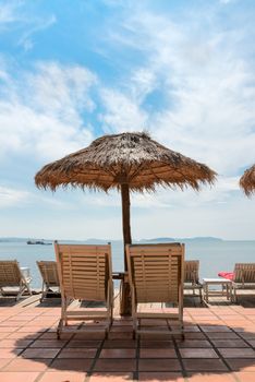 Vacation Concept. Relaxing sunbeds on wooden desk near the sea under blue sky.