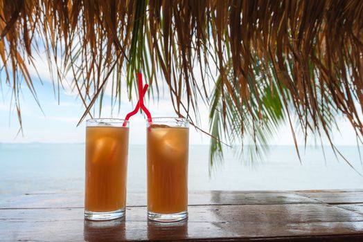 Two summer refresh cocktail drinks or juices in a tropical bar with blue sea and sky on background
