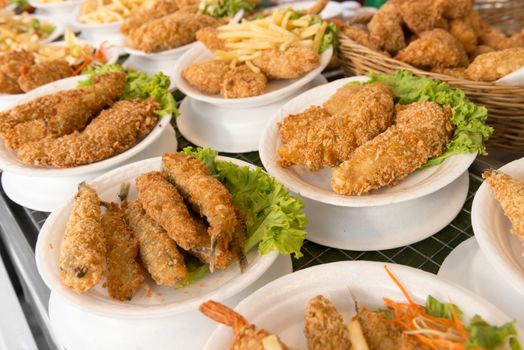 Deep fat fried food assortment in plates on cafe shop shelf