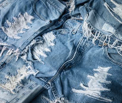 Heap of torn and frayed, threadbare jeans denim shorts