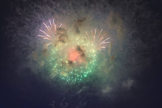 Fireworks in night dark sky with smoke after explosions