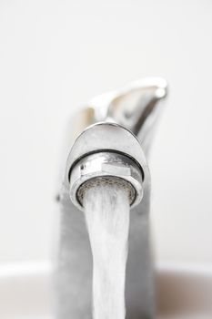 Front view of modern style opened dirty faucet closeup view on white tiles background with small depth of field