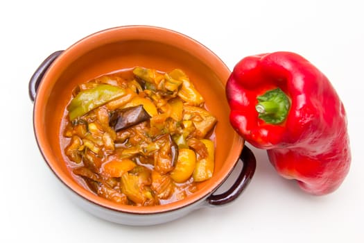 Sweet and sour peppers in the clay pot on white background