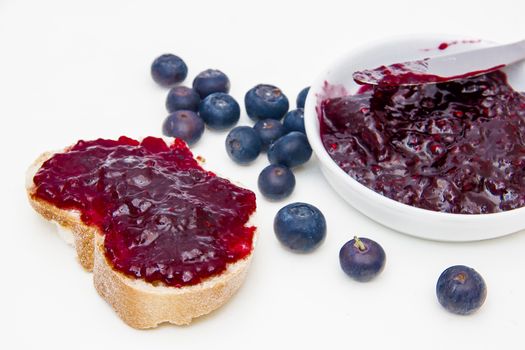 Blueberry jam on bread slices on a white background