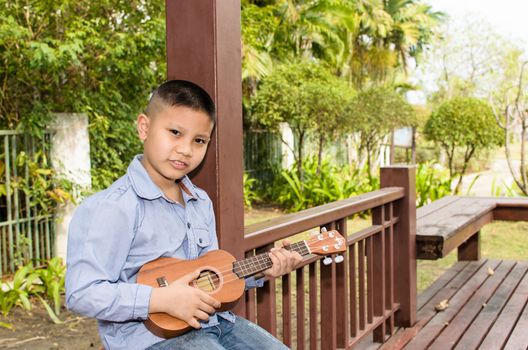 The boy playing the ukulele in the garden.