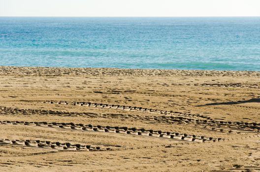 Tractor wheel tracks in golden beach sand