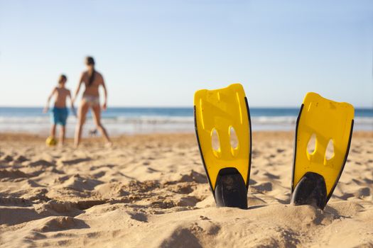 Children playing on the beach behind diver fins