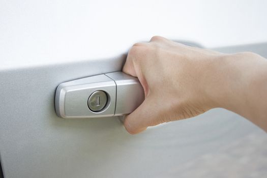 Close up of a man's hand pulling gray car's door handle